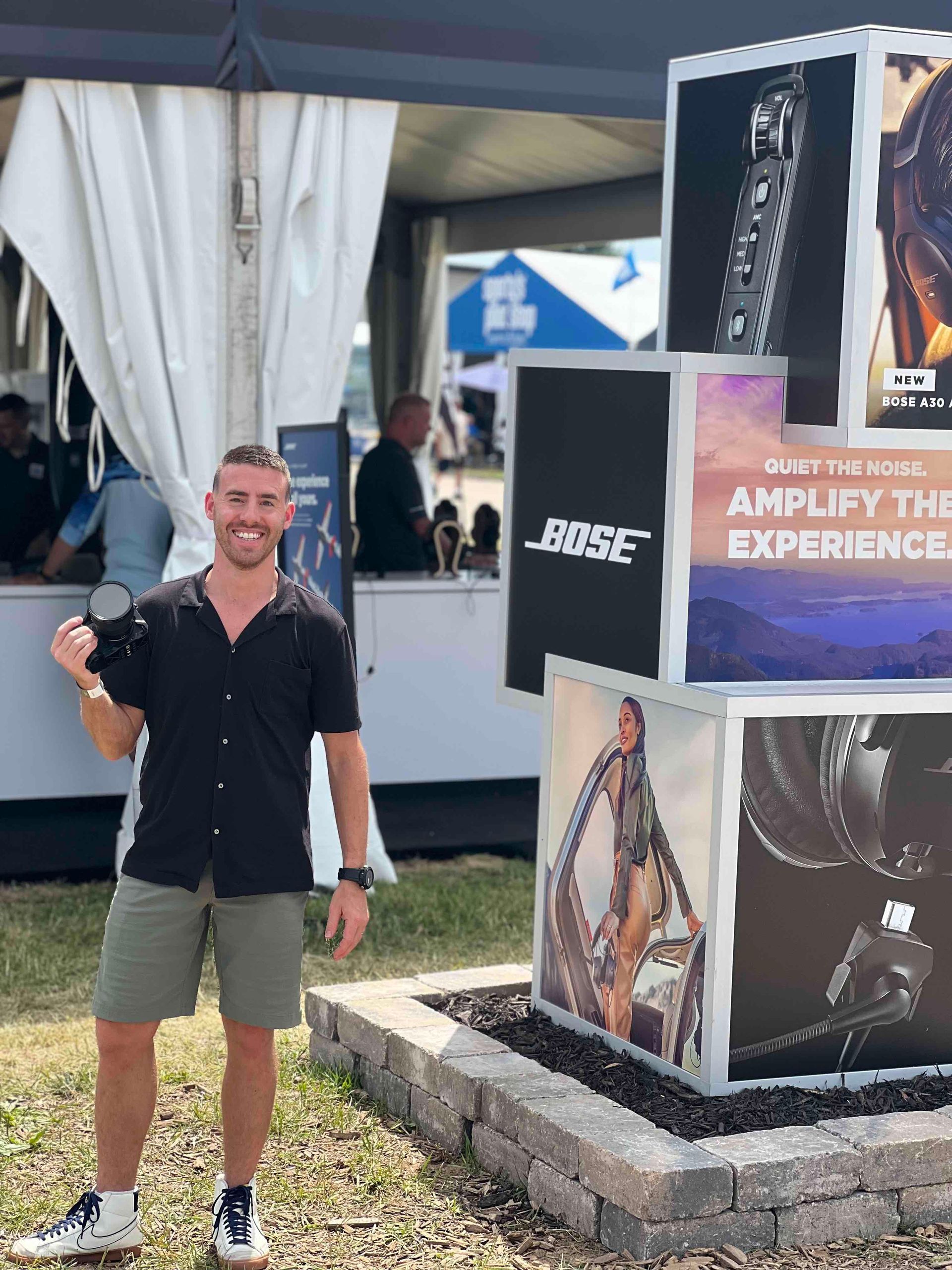 Alex Belville photographing the Bose Aviation exhibit during EAA AirVenture Oshkosh for marketing content.