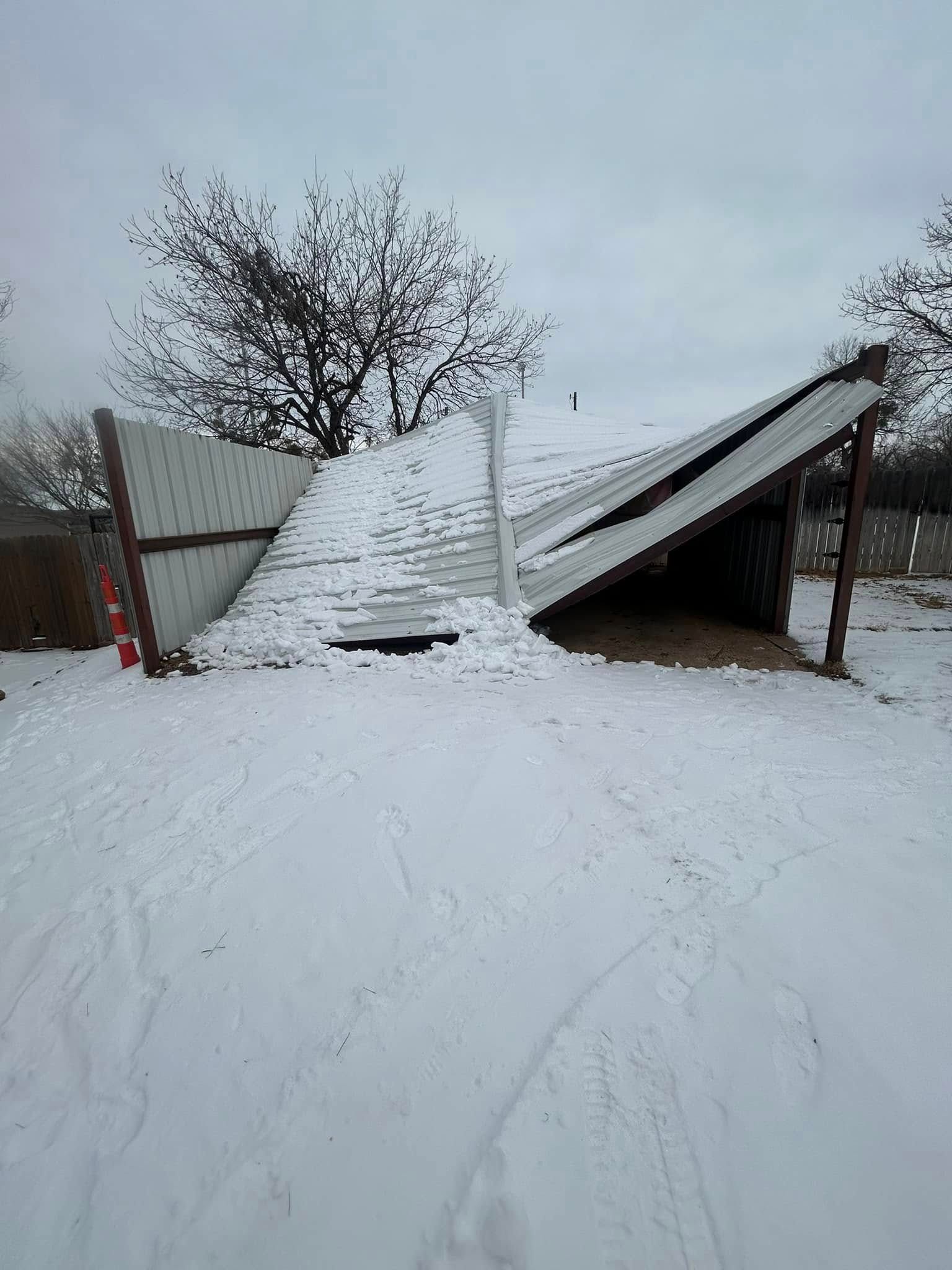 A metal-sided shed has partially collapsed into a pile of snow in a yard during winter.
