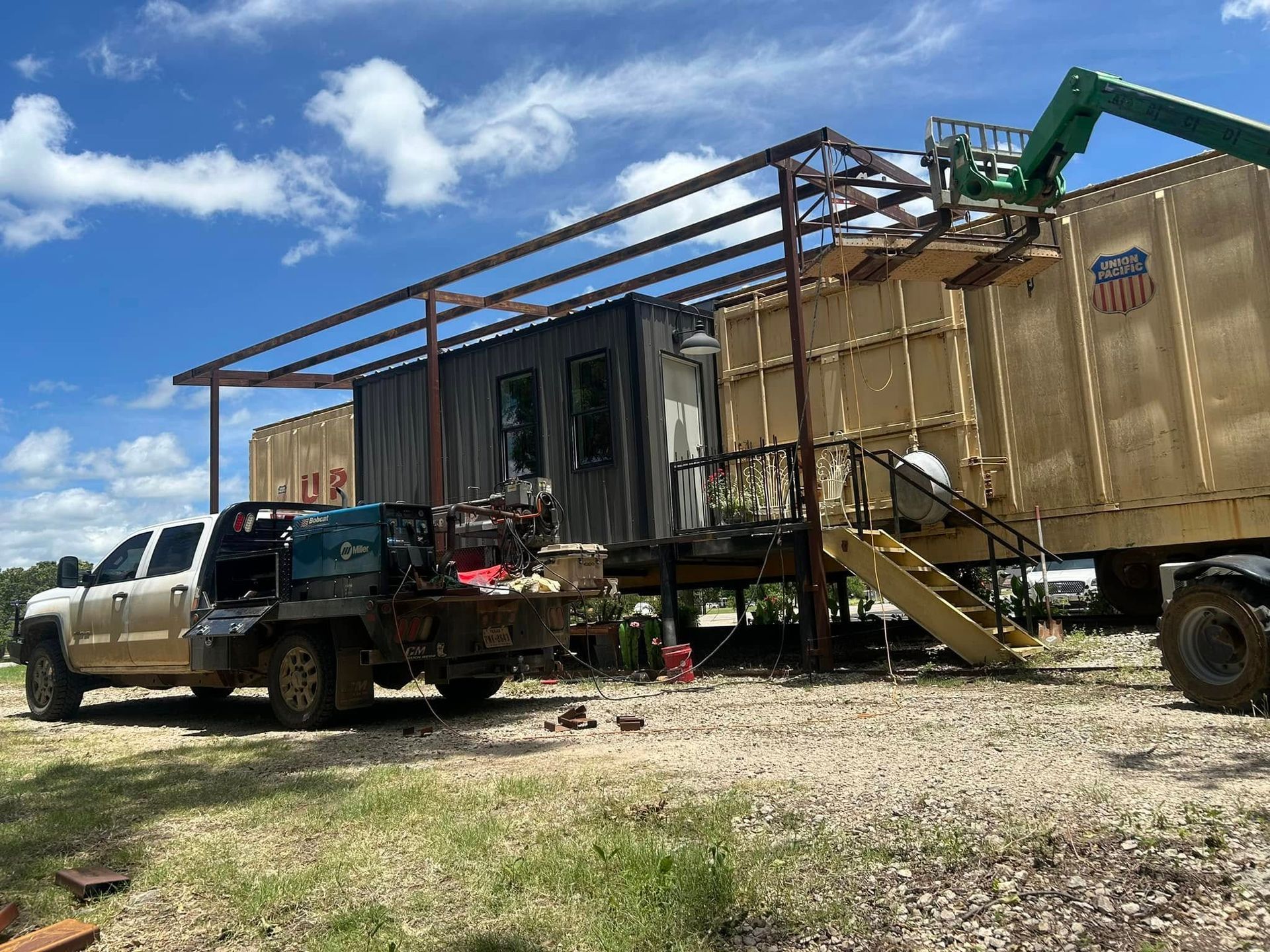 A truck parked next to a modular office structure with a metal frame canopy under a blue sky.