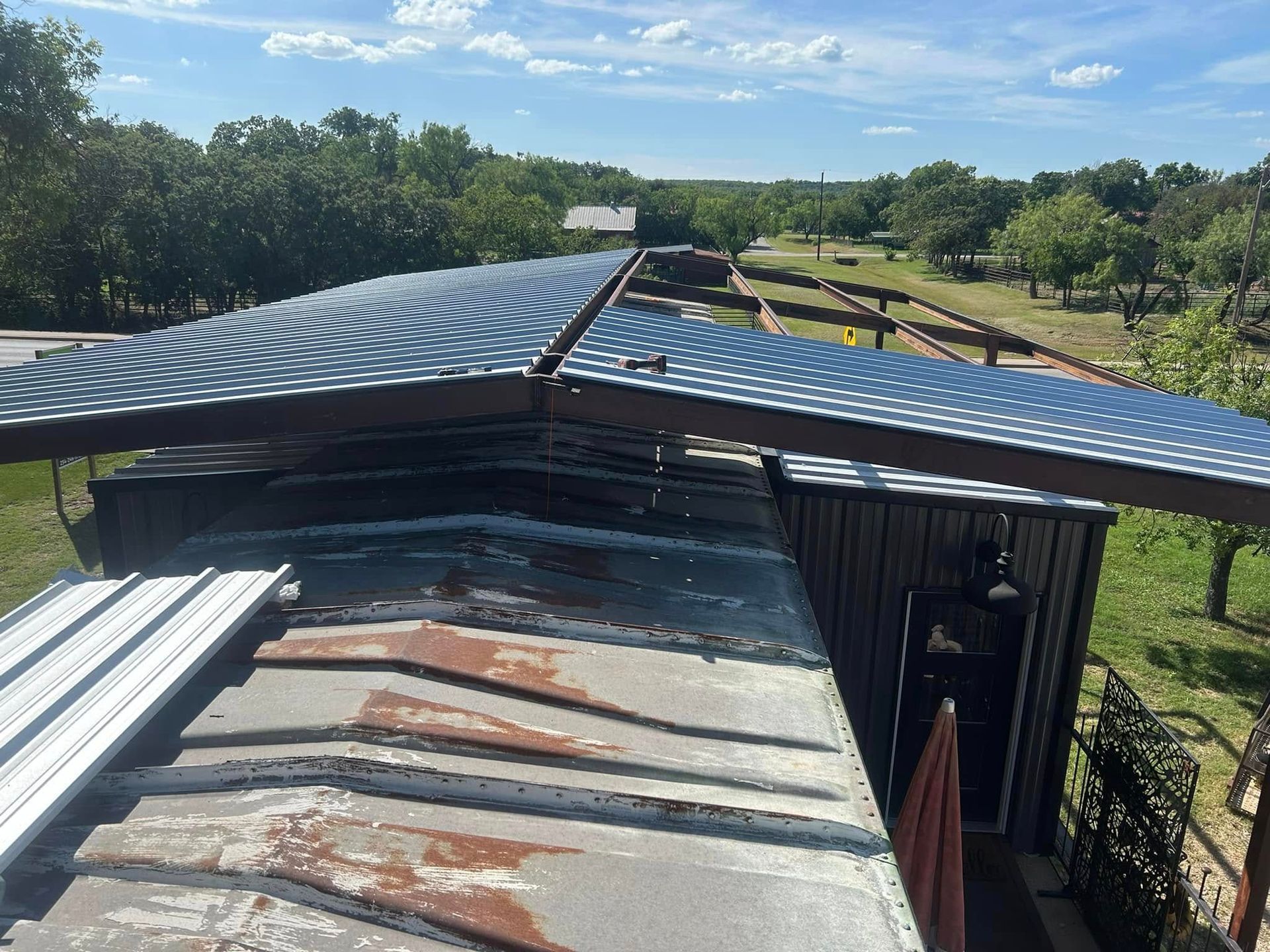 An elevated, V-shaped blue patterned roof section installed over a weathered, metallic structure outdoors.
