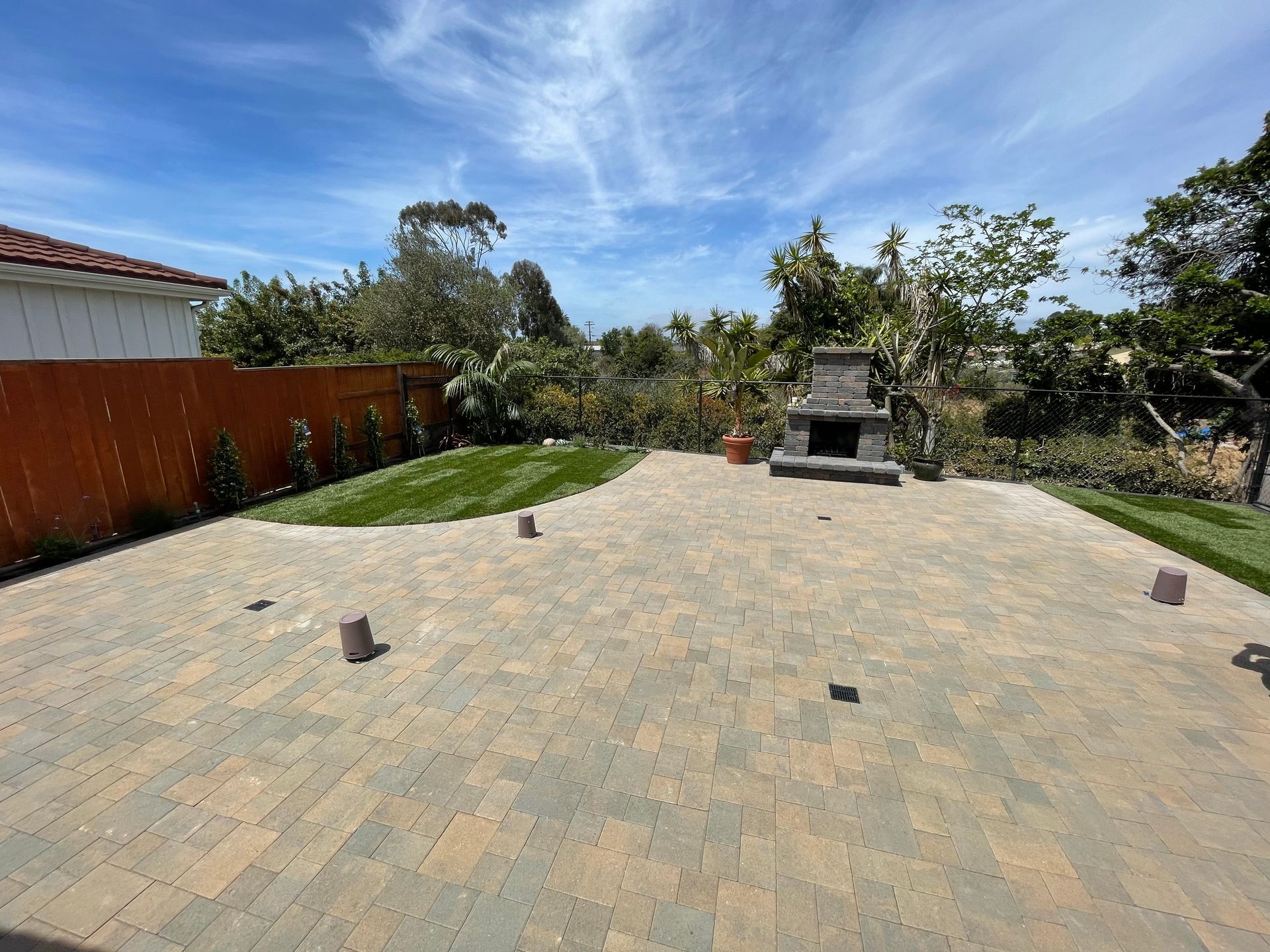 backyard patio with pavers and outdoor fireplace in modern san diego landscape design