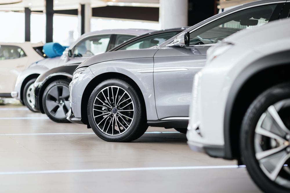 Row of parked cars in a bright indoor showroom, with a silver car in the foreground