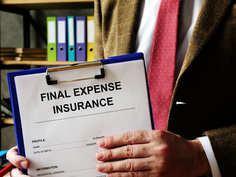 Person holding clipboard labeled “Final Expense Insurance” in an office setting