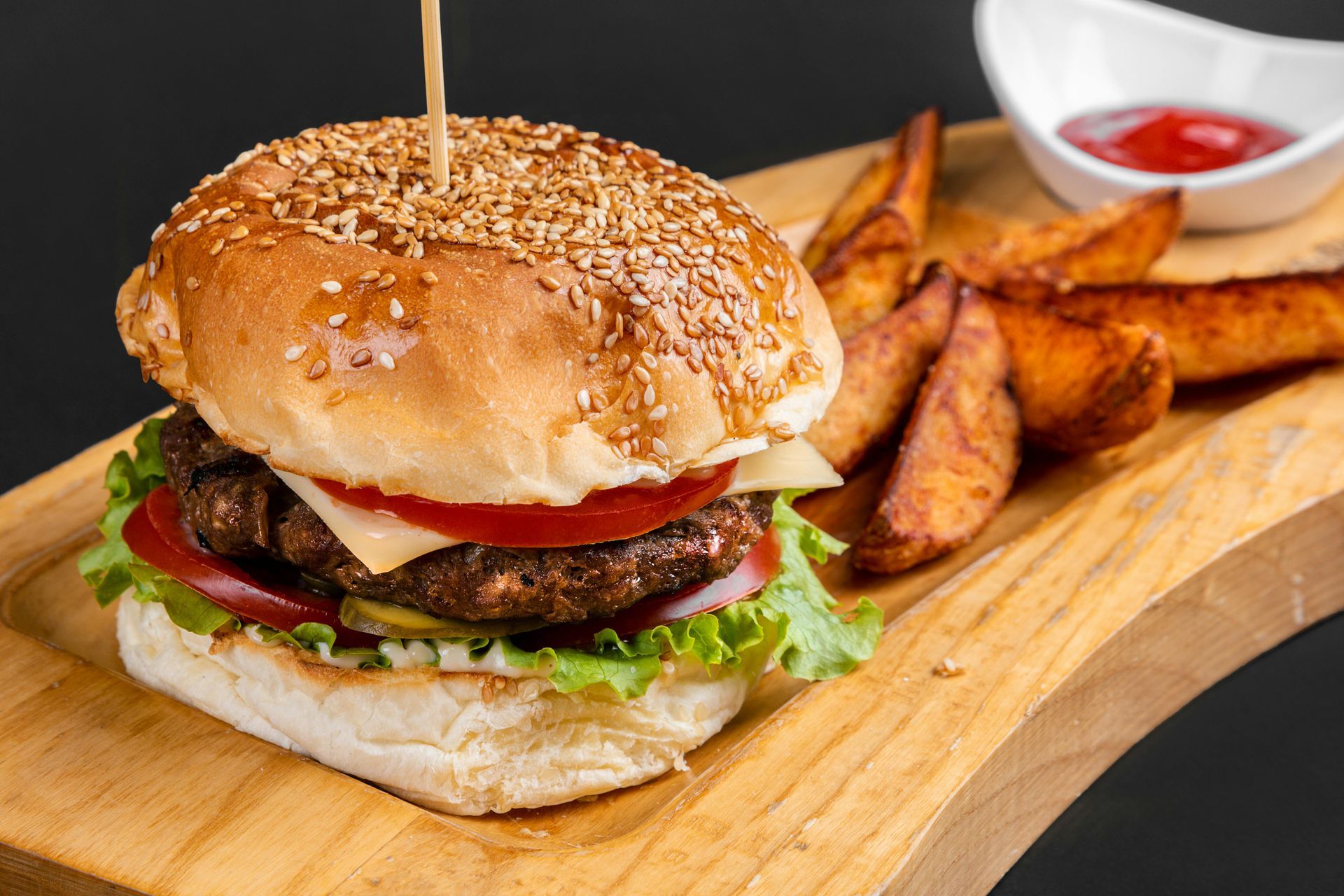 Hamburger with fries and ketchup on a wooden board.