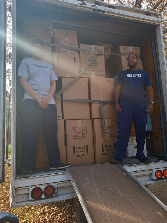 Two delivery men are loading boxes into a van.