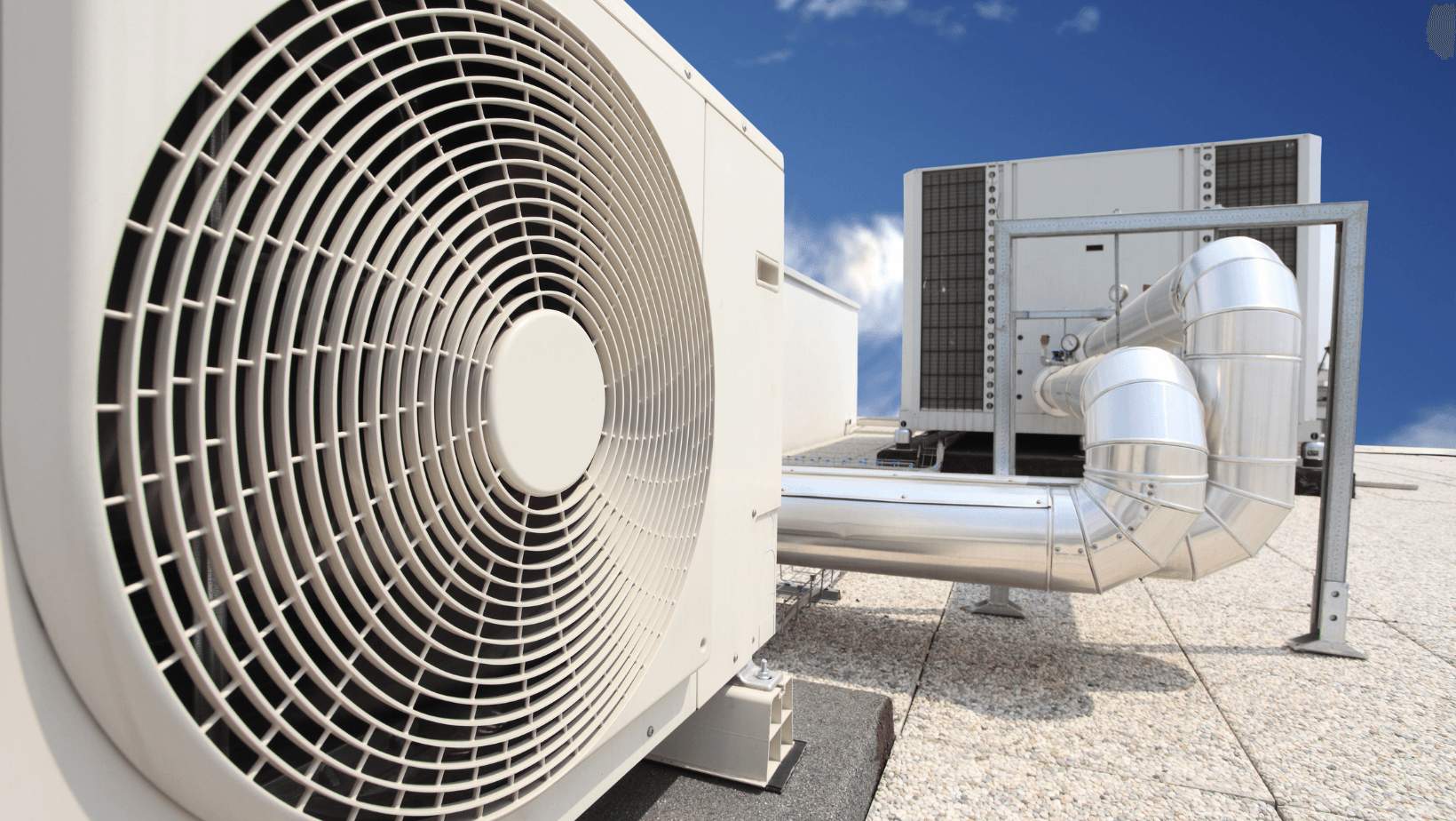 Large rooftop HVAC units with metal ducts under a clear blue sky