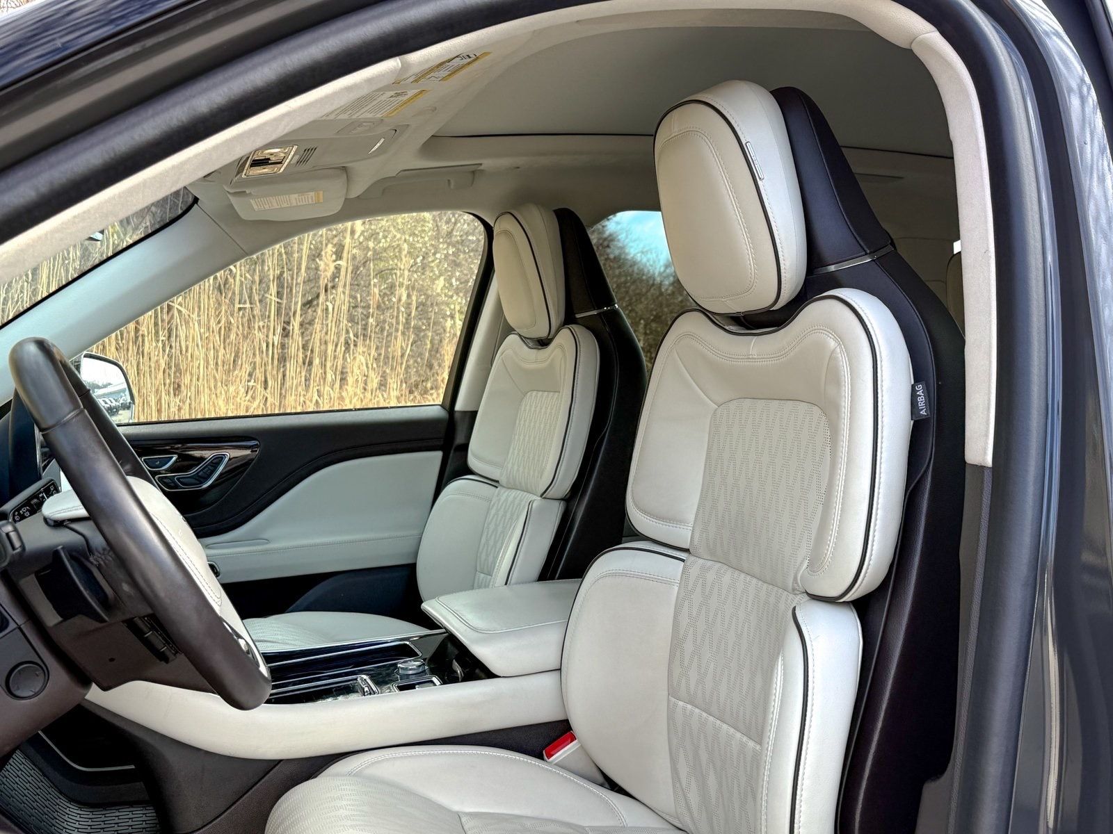 Luxury car interior with beige leather seats and open driver-side door