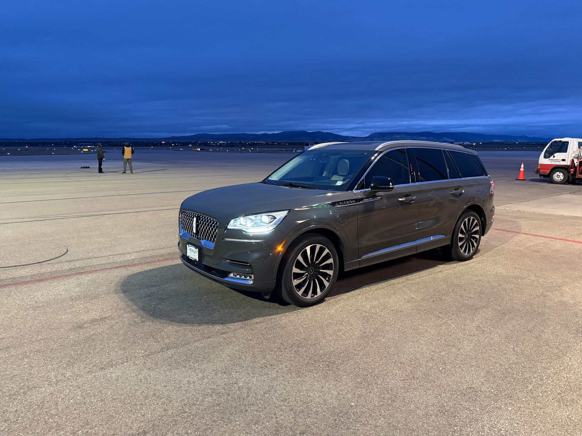 Dark gray SUV parked on an open lot at dusk, with a cloudy blue sky in the background.