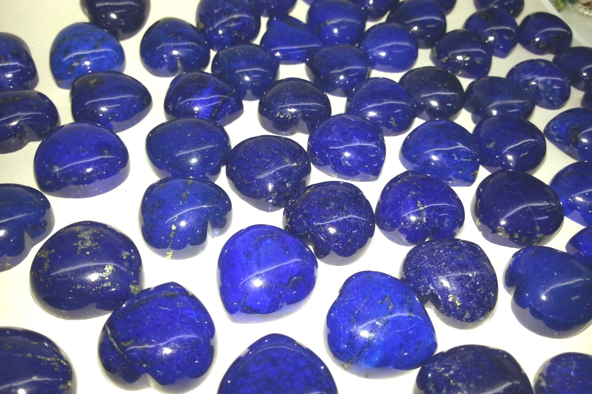 Una collezione di gemme di lapislazzuli levigate a forma di cuore, di un blu intenso con delicate sfumature dorate.