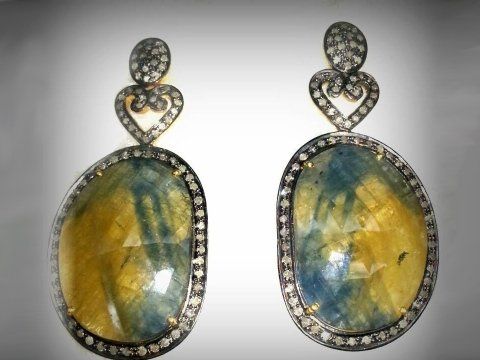 Orecchini pendenti con grandi pietre ovali sfaccettate bicolore gialle e blu, circondate da diamanti e con elementi a forma di cuore.
