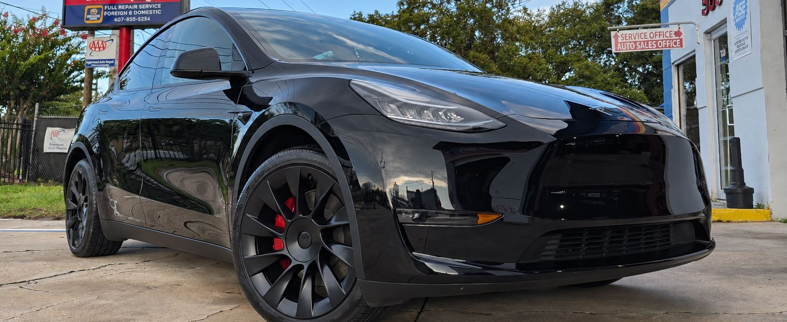 Black sports car parked outdoors in front of a building, low front-angle view
