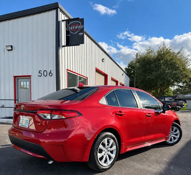 Red sedan parked outside a metal building with red-trimmed windows under a blue sky