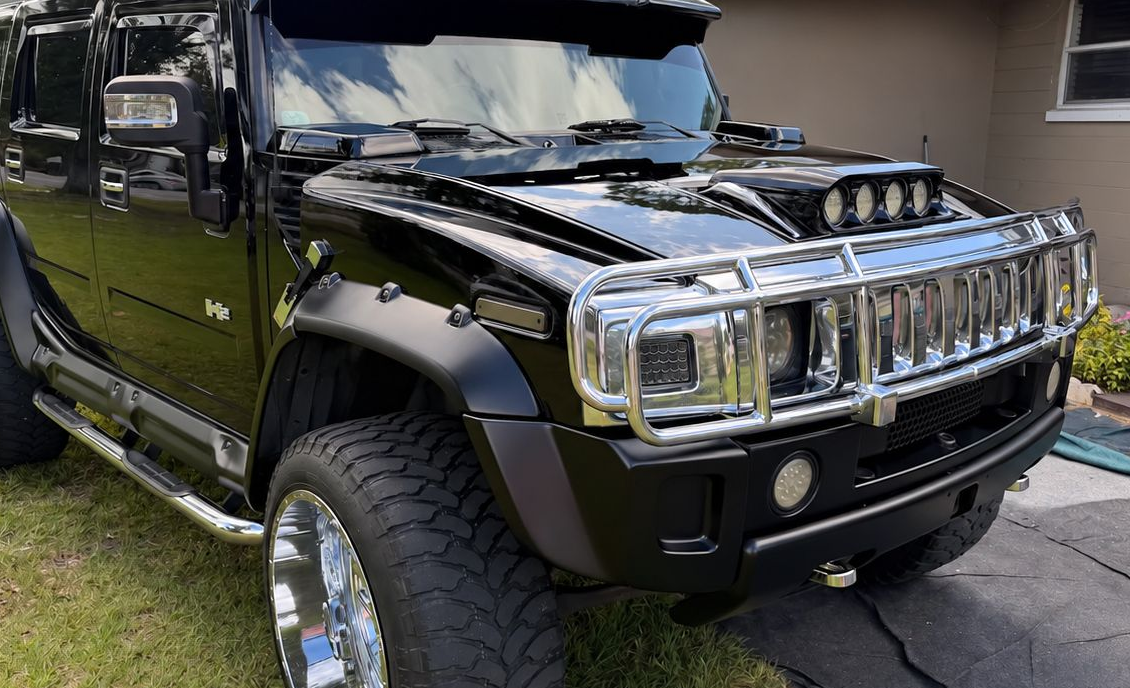 Black Hummer-style SUV with chrome grille and roof lights parked on a driveway
