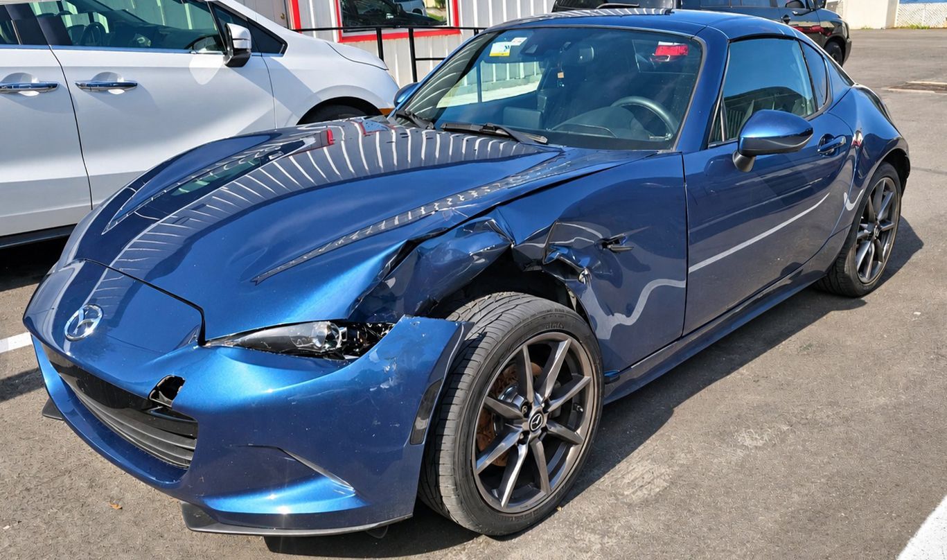 Black sedan with front-end damage parked in a lot