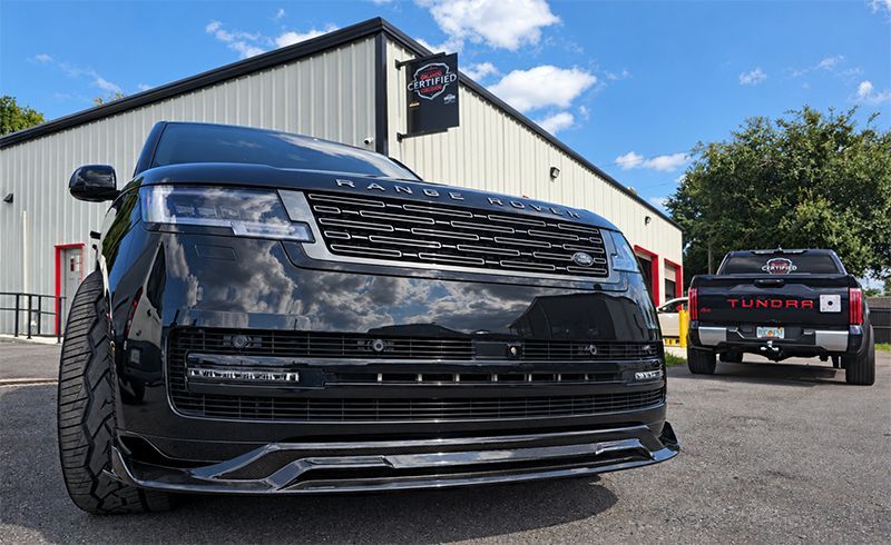 Black SUV with custom grille parked outside a building on a sunny day