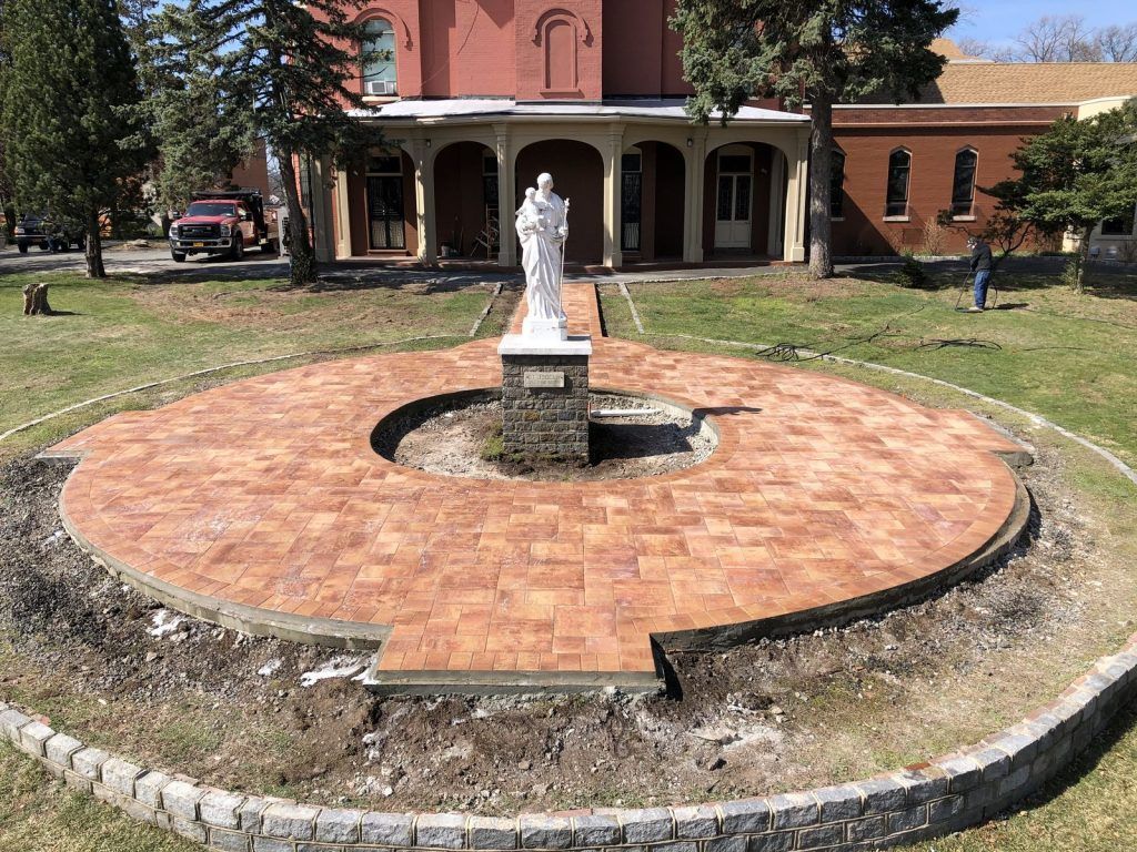 There is a statue of jesus in the middle of a circle in front of a building. There is a statue of jesus in the middle of a circle in front of a building.