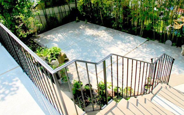 A set of stairs leading up to a patio with a metal railing.