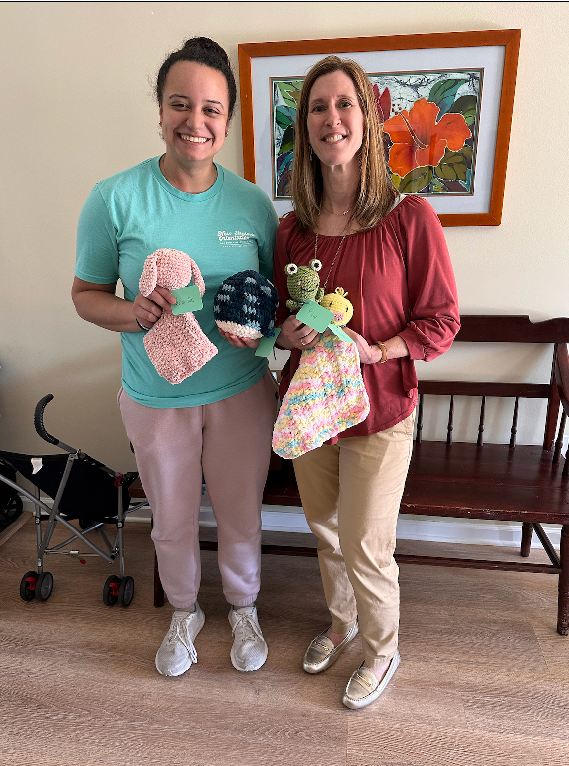 Two women holding crocheted toys and smiling indoors.