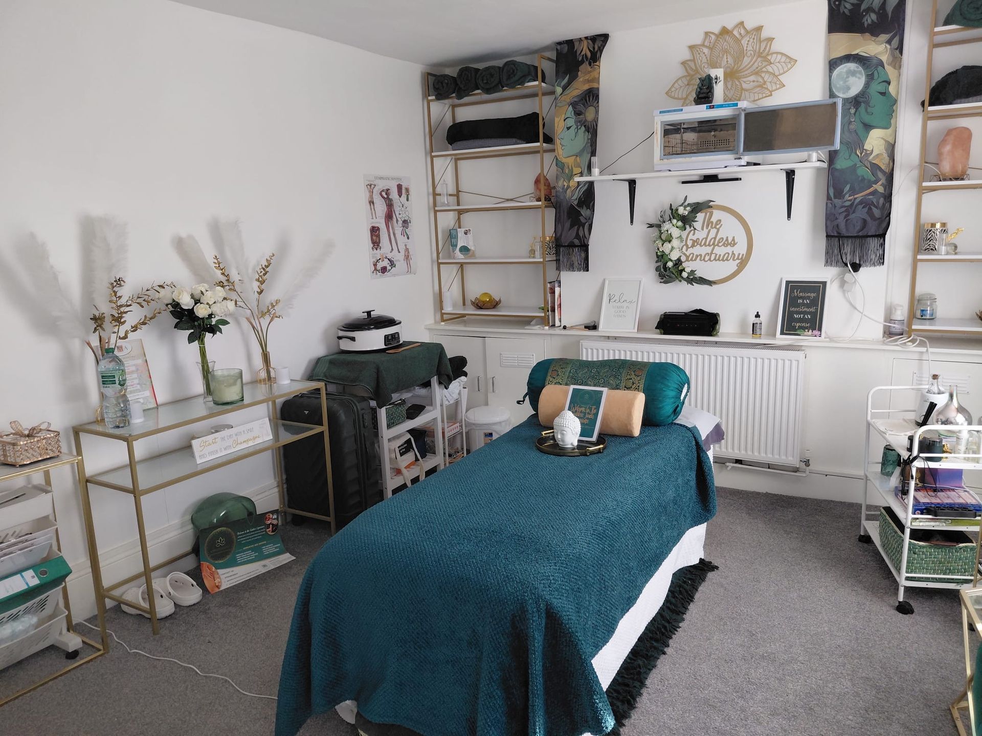 Cozy bedroom with teal bedspread, white walls, shelves, plants, and decorative wall art