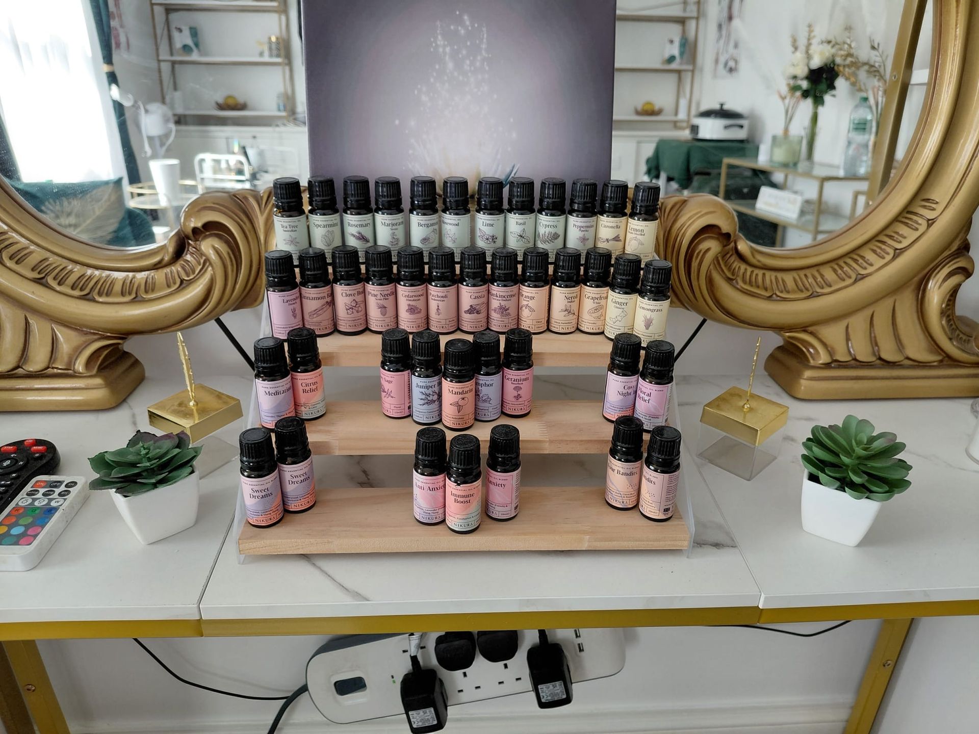 Display of pink and black bottles arranged in rows on a white table with ornate gold mirrors on both sides