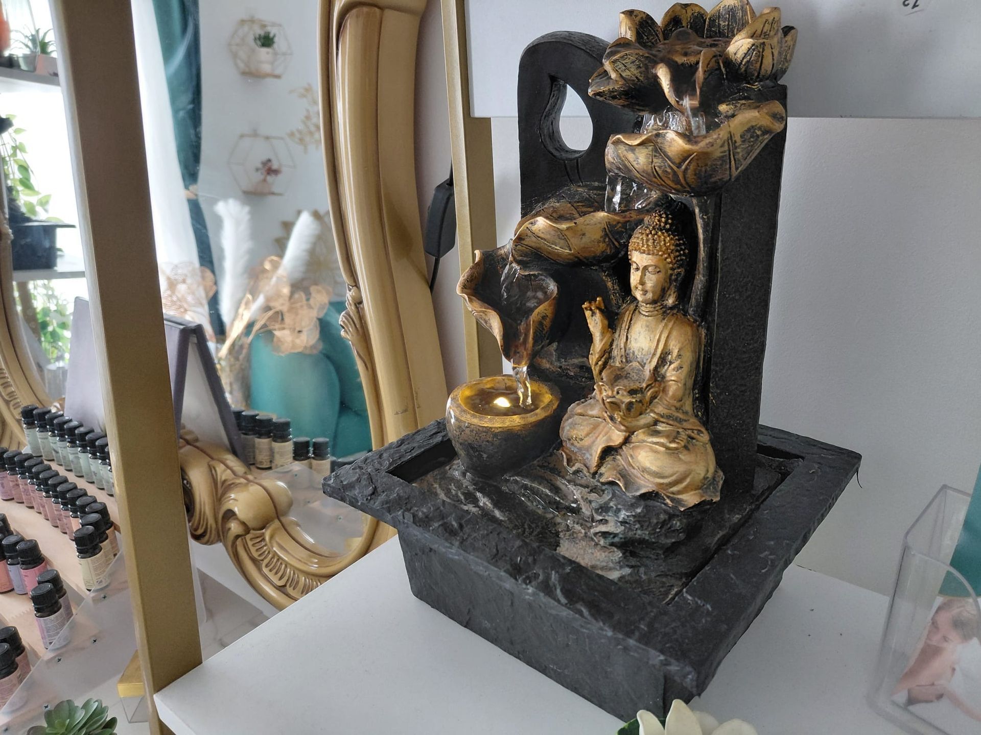Gold and black decorative fountain statue on a tabletop, with a small bowl and seated figure
