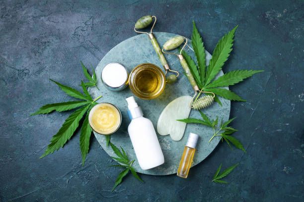 Cannabis leaves and CBD oil bottles arranged on a gray tabletop