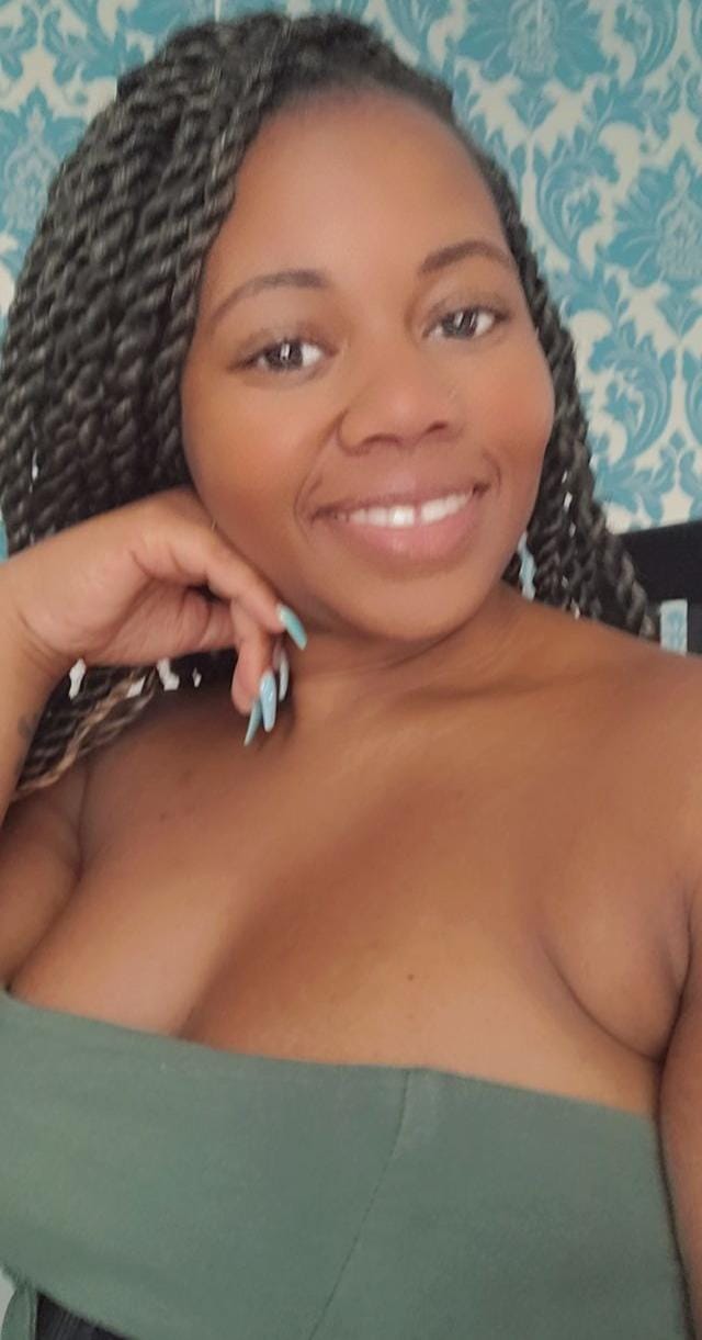 Smiling person in a green off-shoulder top against a blue patterned background