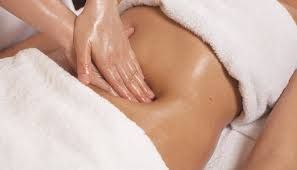 Person receiving a lymphatic drainage massage on stomach area on massage table.