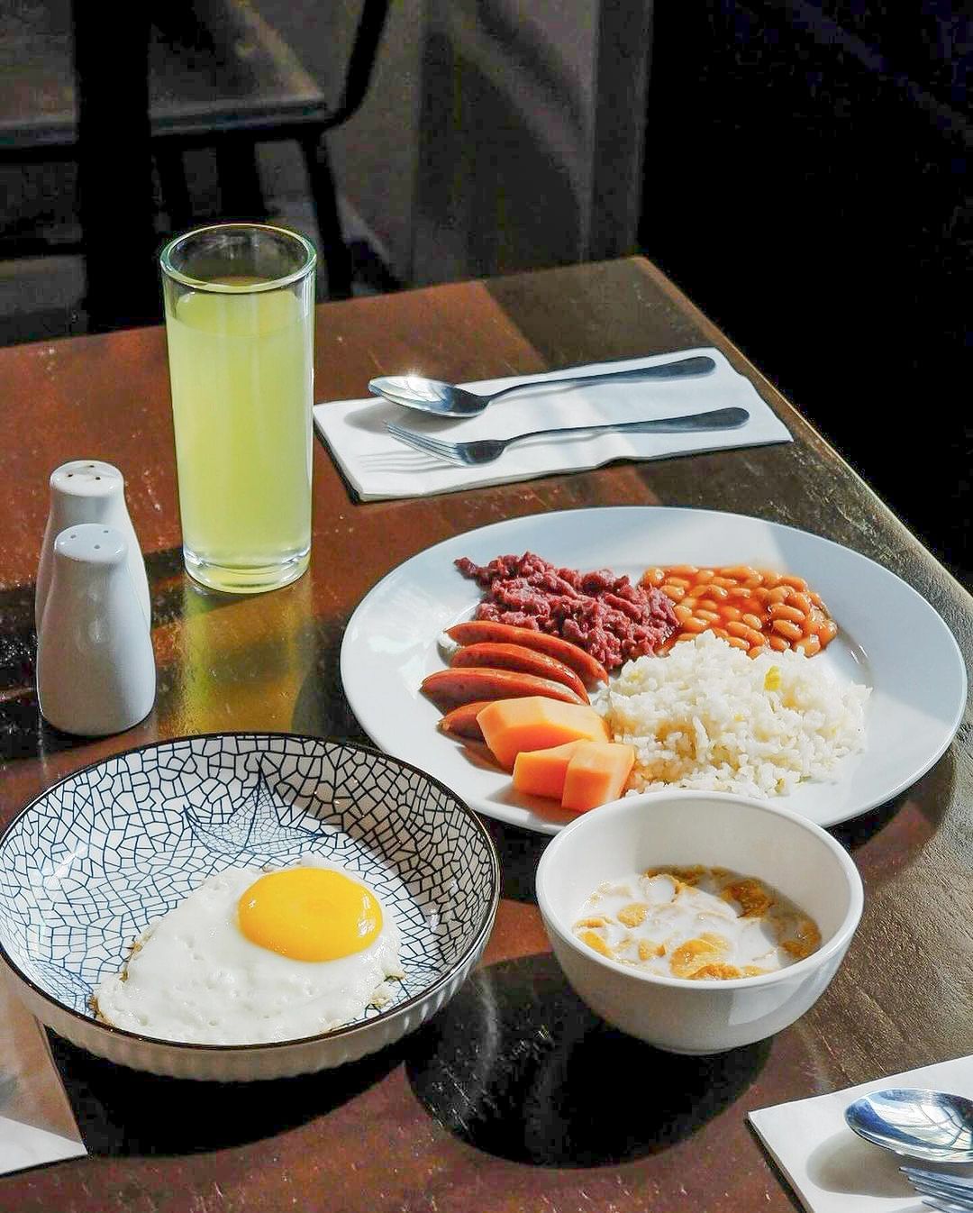 Filipino breakfast with fried egg, rice, sausage, beans, and juice at Y2 Re