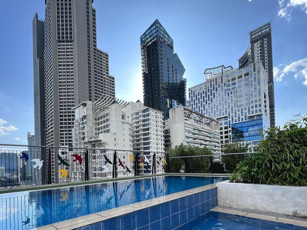 Rooftop pool at Y2 Residence Hotel Makati with colorful bird cutouts on the railing and a view of the city skyline