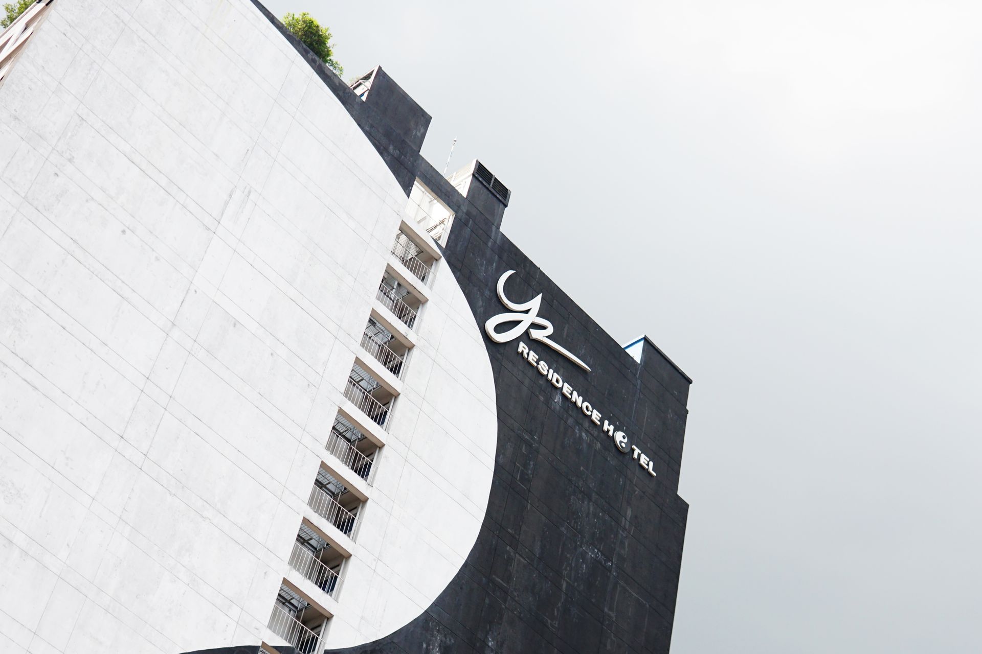 Low-angle view of the Y2 Residence Hotel sign on the black and white yin-yang facade of the building in Makati