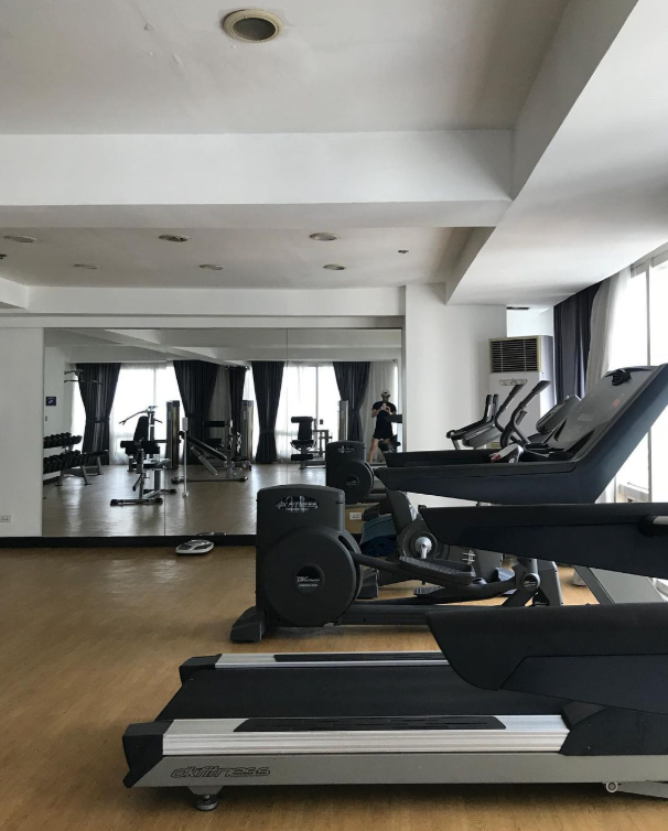 Gym interior with exercise machines, mirrors, and a window.