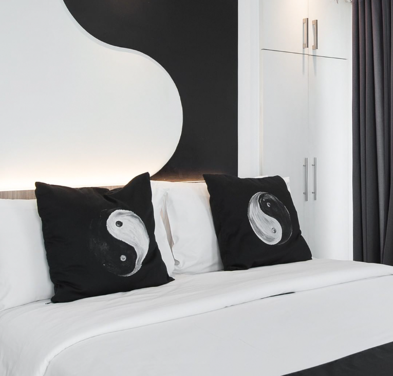 A bed with two black pillows with a yin yang design signature of Y2 Residences Hotel