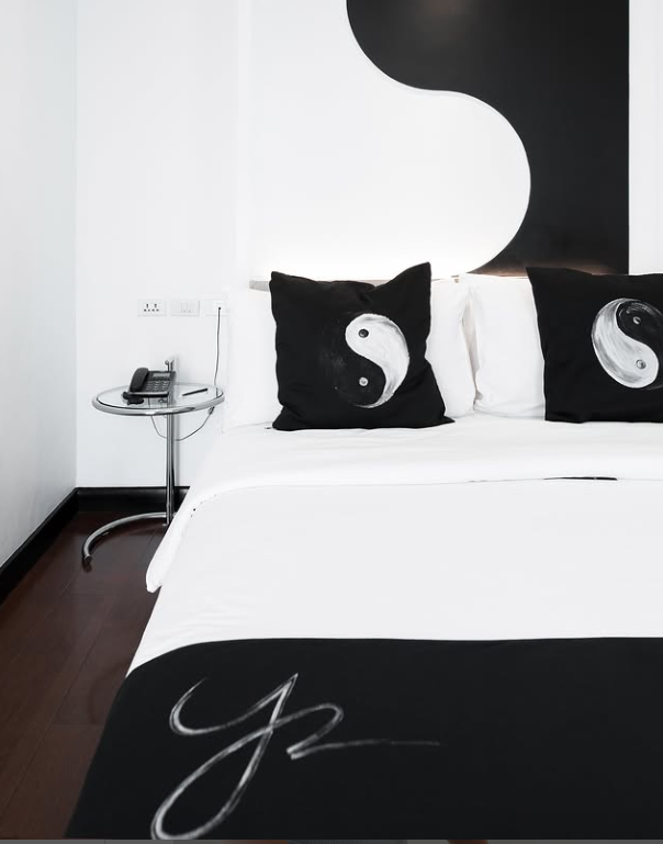 Bedroom with white bedding, black and white yin yang pillows, and a yin yang wall design.