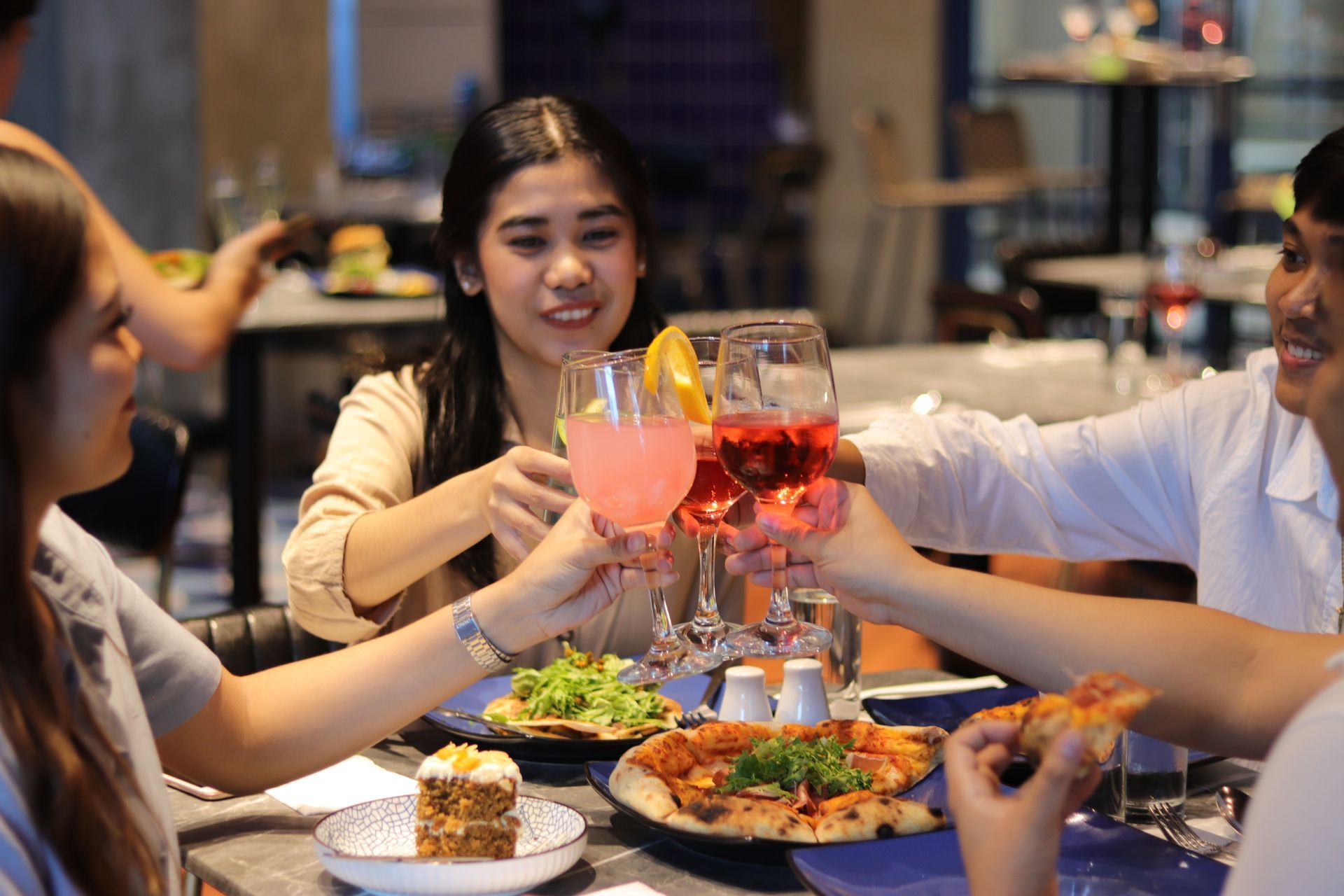 Friends toasting drinks over pizza, salad, and carrot cake at Y2K Gastropub in Y2 Residence Hotel Makati