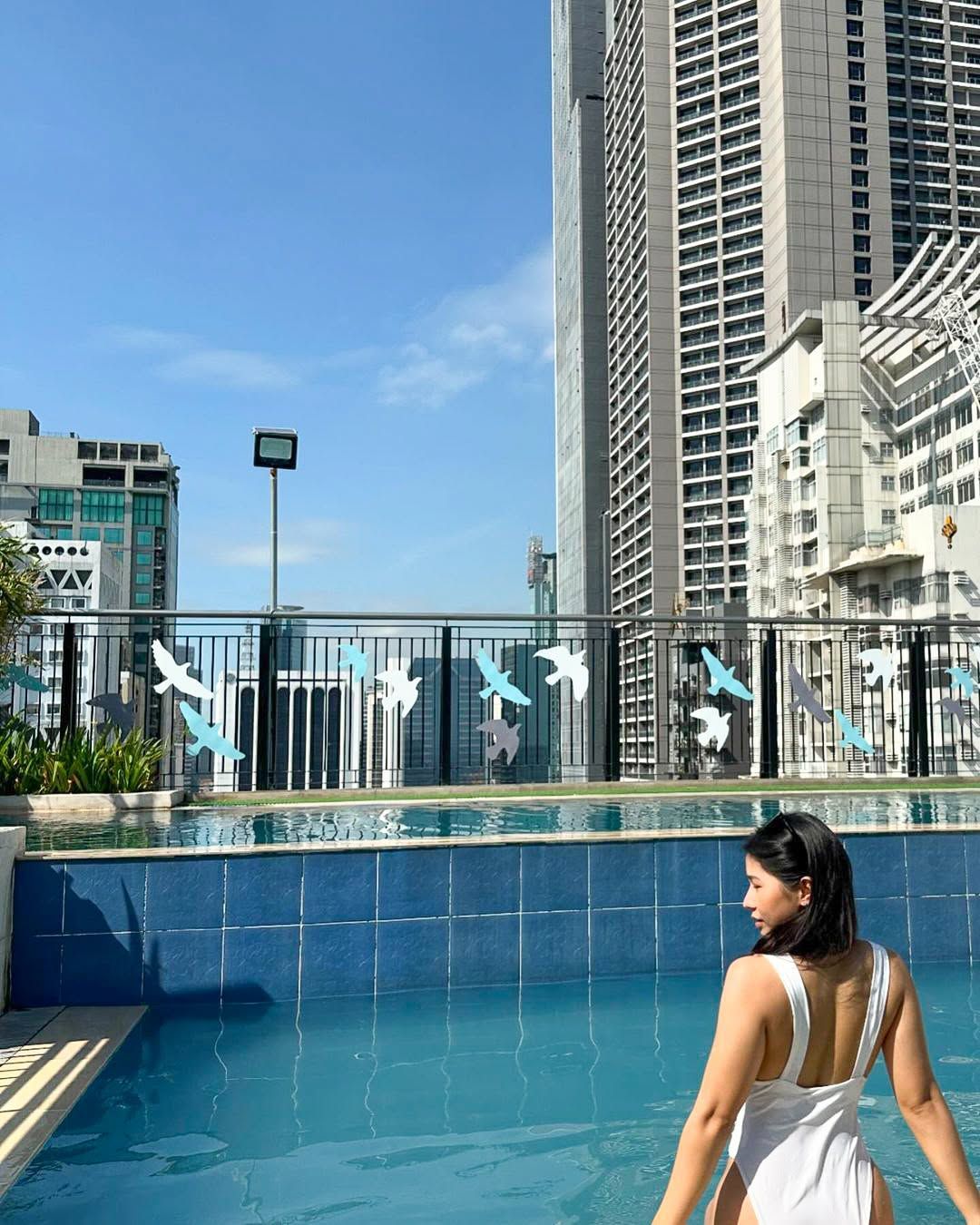 Woman in white swimsuit at Y2 Residence Hotel rooftop pool, Makati