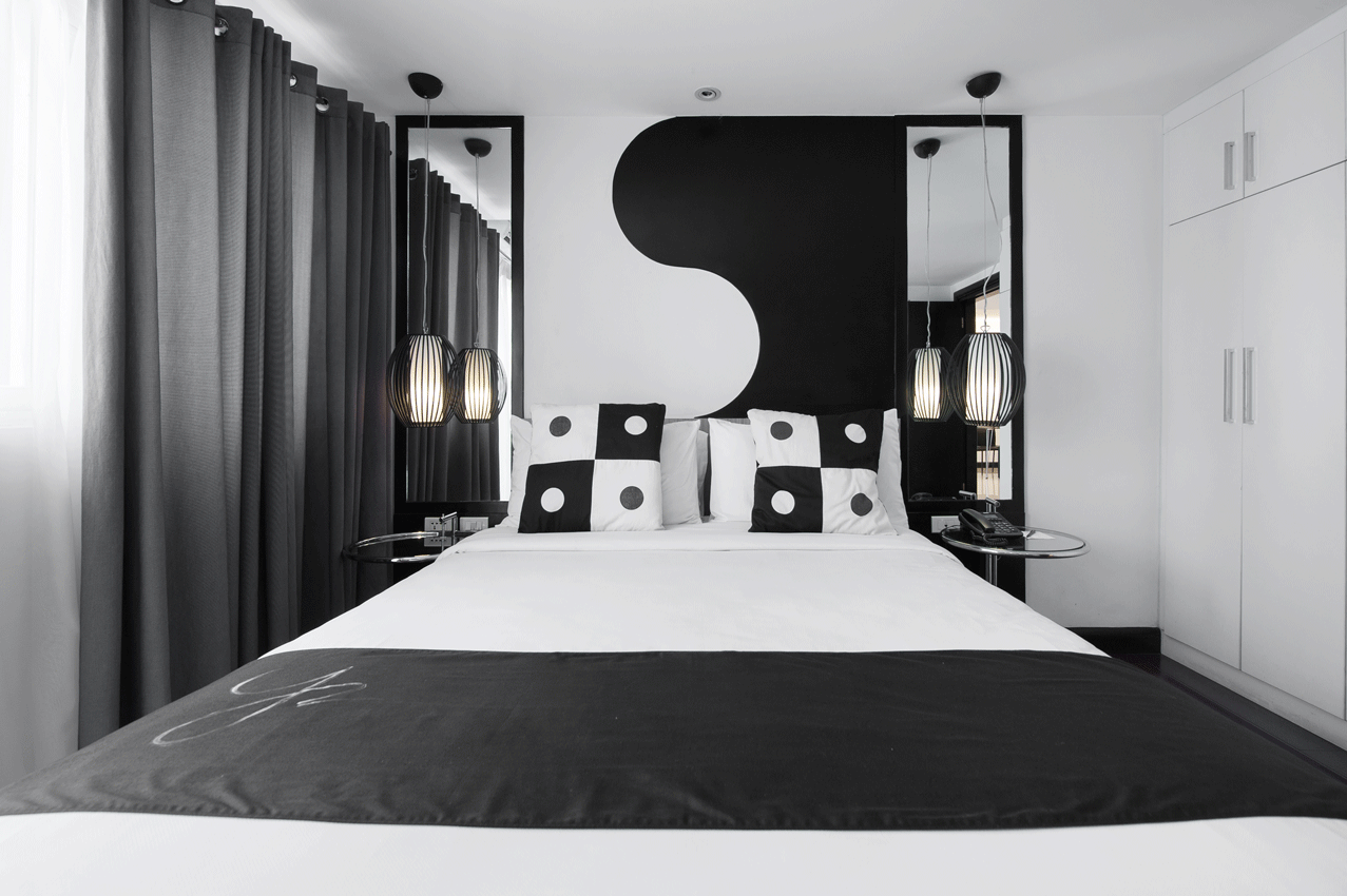 Modern bedroom featuring a bed with black and white decor, Yin-Yang wall art, and a floor-to-ceiling curtained window.