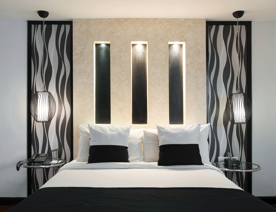 Bedroom with a bed, centered beneath decorative wall panels in black and white, with built-in lights.