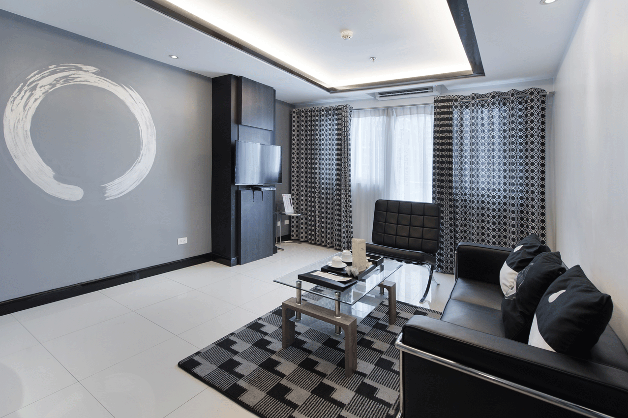 Separate living area with sofa and TV in a One Bedroom Deluxe at Y2 Residence Hotel, Poblacion Makati
