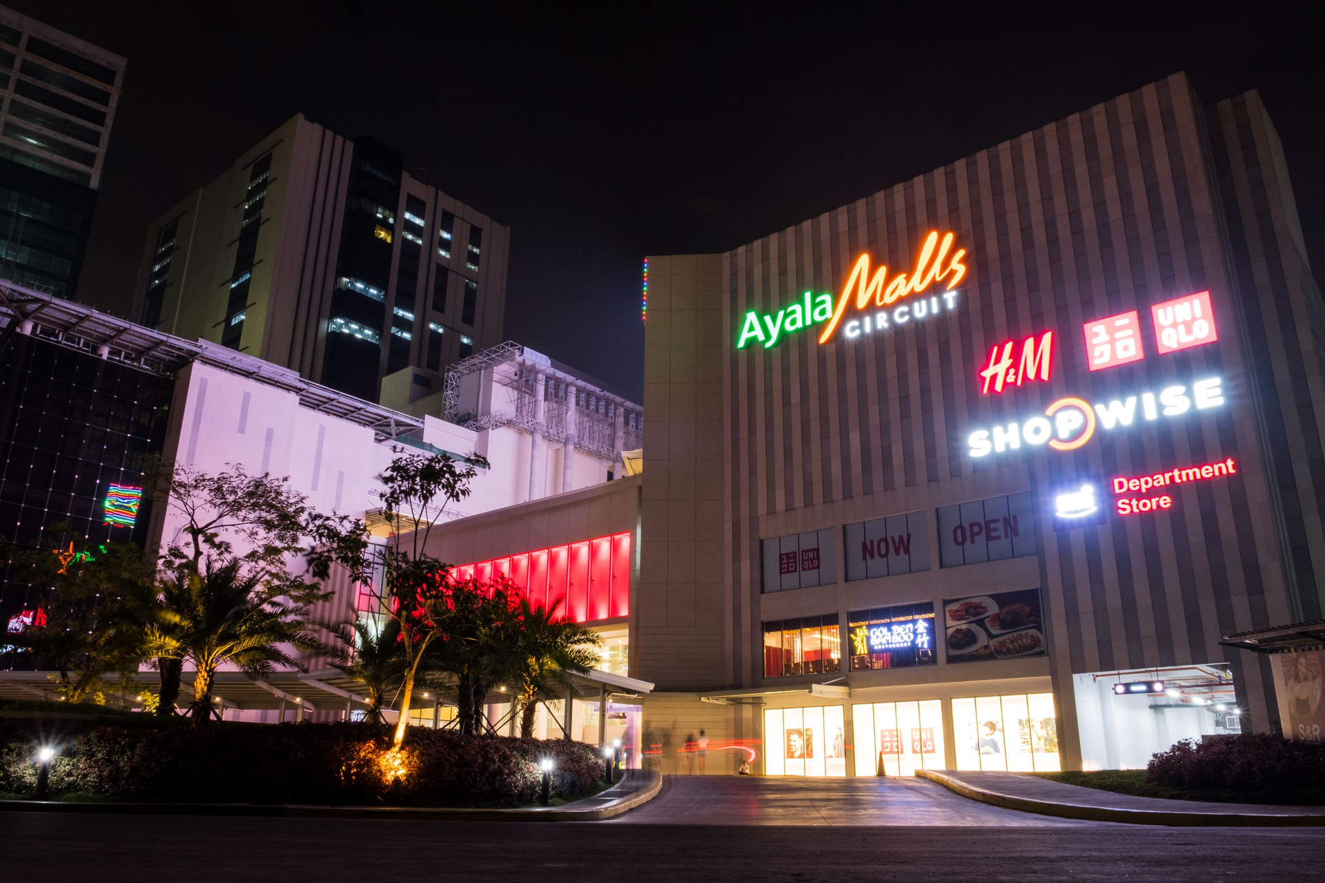 Brightly lit shopping mall storefront with neon signs in Poblacion Makati.