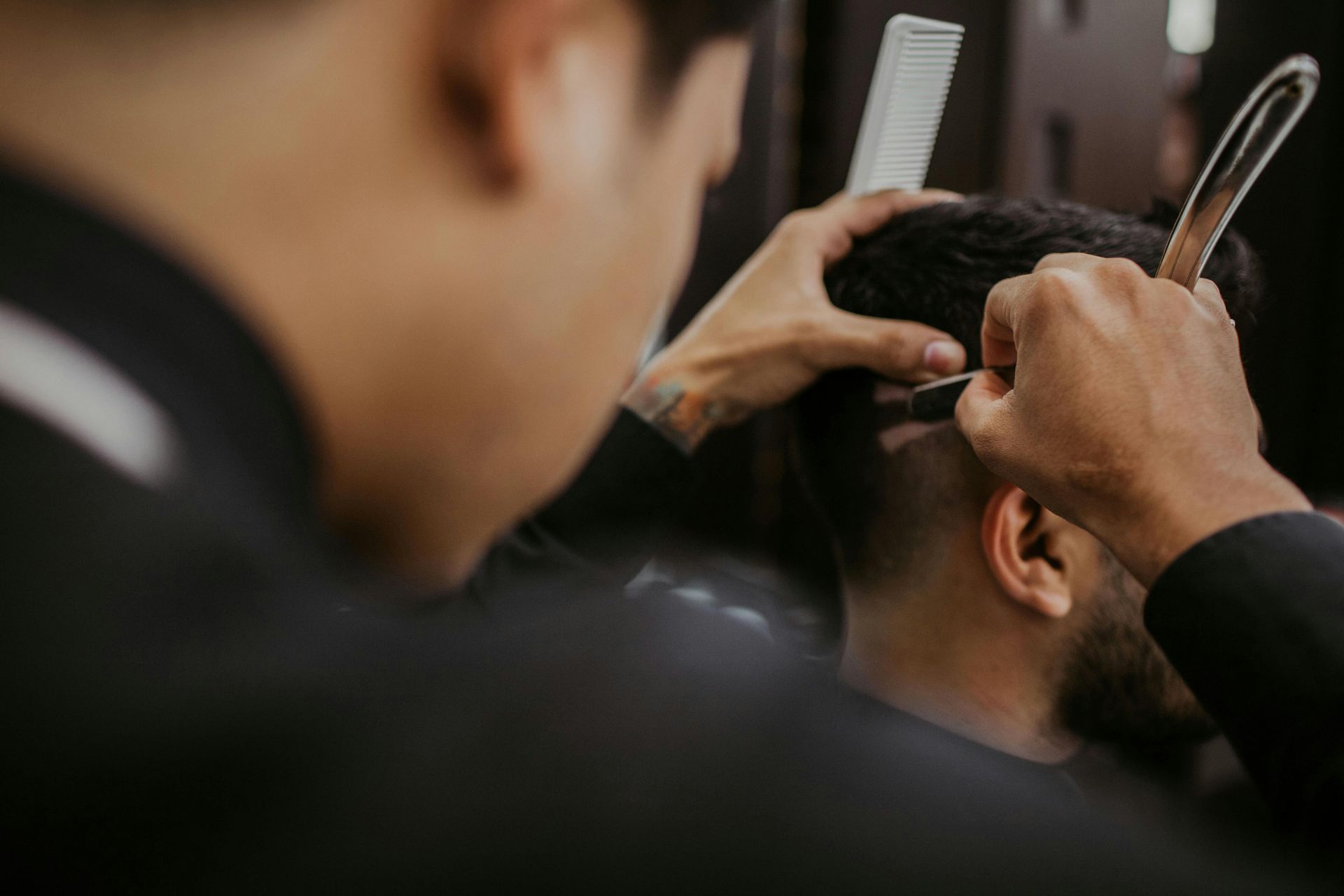 Hairdresser trimming a client’s hair with scissors and comb in a barbershop