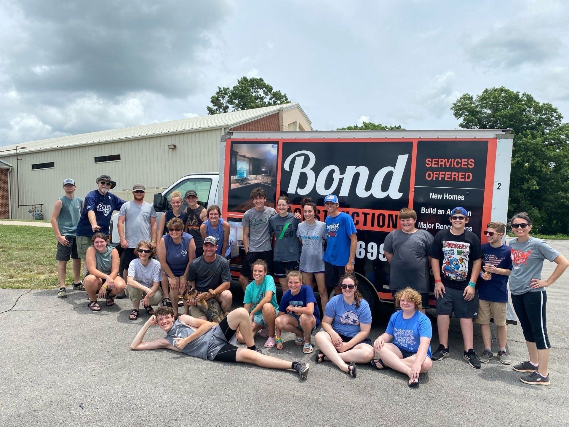 Youth Group posing by a Bond Construction truck in front of a building.