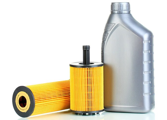 Oil filter and oil bottle on white surface. The filter is yellow, the bottle is silver.