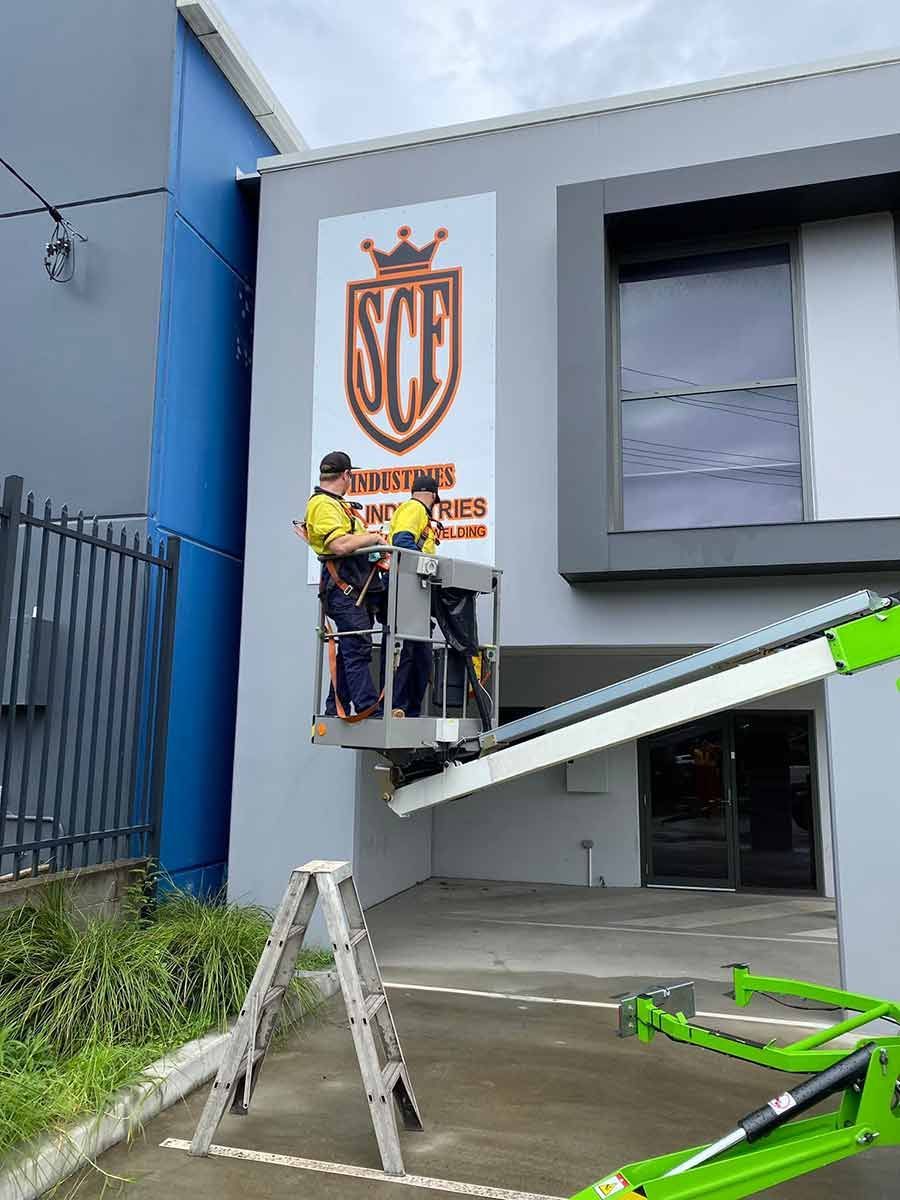 A Man is Standing on a Construction Lift in Front of a Building — SCF Industries Pty Ltd in Albion Park Rail, NSW