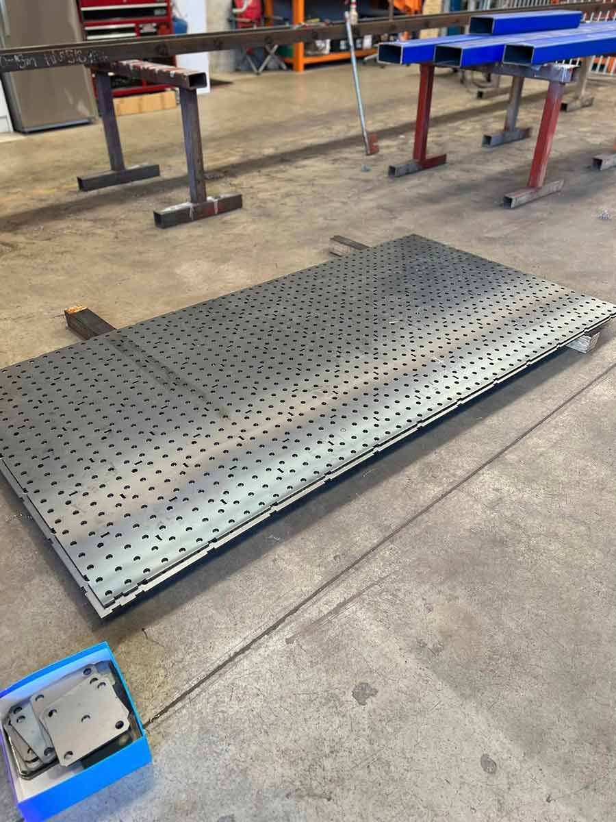 A Large Metal Plate With Holes in It is Sitting on a Concrete Floor — SCF Industries Pty Ltd in Albion Park Rail, NSW