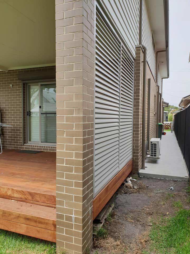 A Brick House With a Wooden Deck and a Sliding Glass Door —  SCF Industries Pty Ltd in Albion Park Rail, NSW