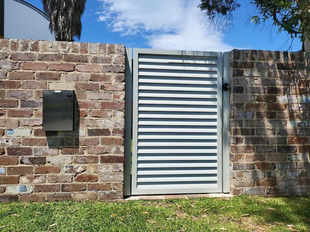 A Brick Wall With a Gate and a Mailbox in Front of It — SCF Industries Pty Ltd in Shellharbour, NSW