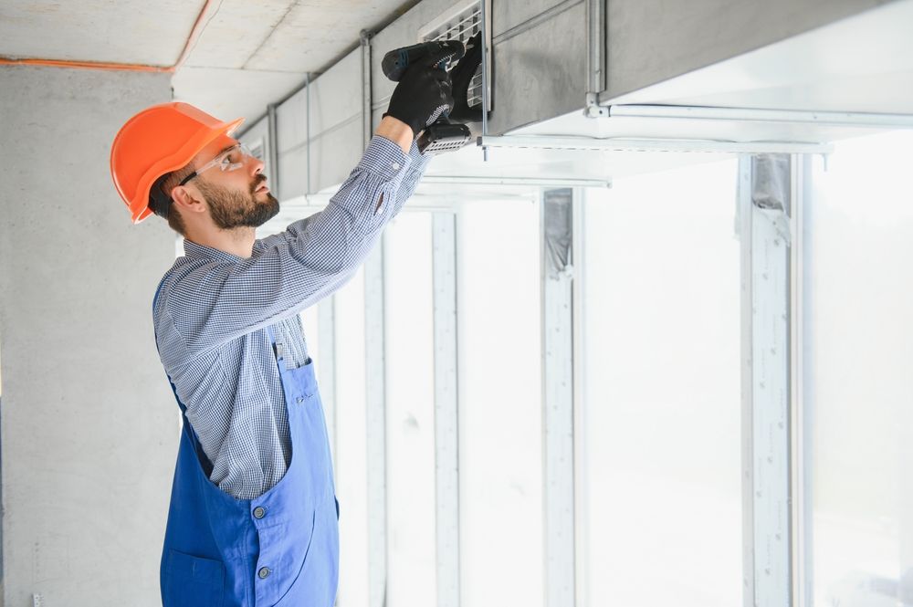 A man is using a drill to install a ceiling.