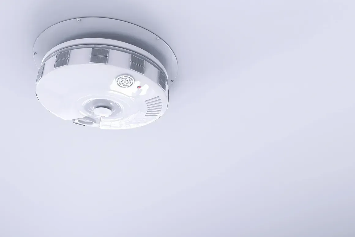 A smoke detector is mounted to the ceiling of a room.