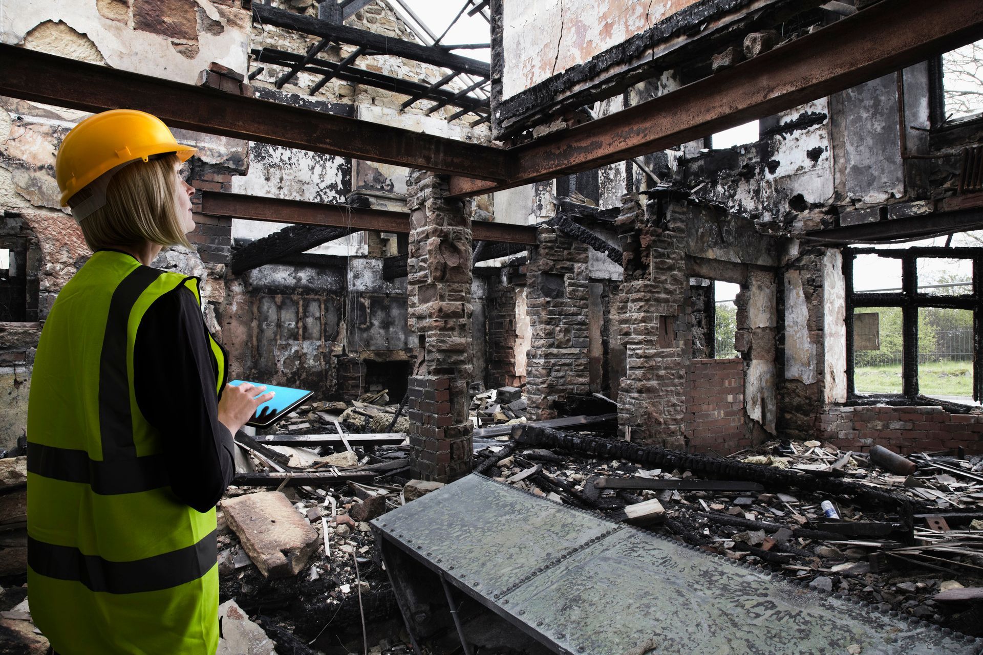 A woman with a security vest inside fire-damaged property.
